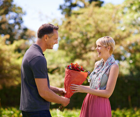 Canvas Print - Smile, couple and present of flowers in nature outdoor, bonding and date on valentines day. Bouquet, man and woman with gift for love, care and romantic connection of people laughing at park together