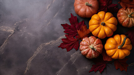 A group of pumpkins with dried autumn leaves and twig, on a dark red color marble