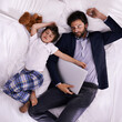 © Y.A./peopleimages.com - Tired, businessman and sleep with son, laptop for rest with technology and suit. Father, child and bedroom with fatigue, love and above with freelance peace or remote work for stress management