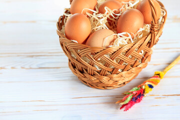 Sticker - Eggs in a wicker basket on a white wooden table, copy space.