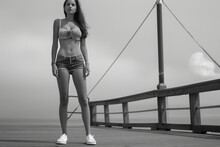 female in a bandeau top, highwaisted shorts, and boat shoes on a pier