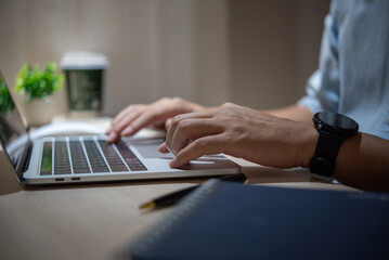 Wall Mural - Hands typing on a laptop keyboard while wearing a smartwatch..