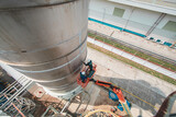 Male industry working at high in a boom liftinspection tank silo
