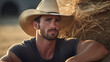 Sexy cowboy with green eyes, sitting next to bale of straw wearing Stetson hat. 