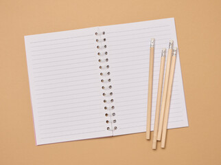 Wall Mural - Open notebook and wooden pencils on brown background