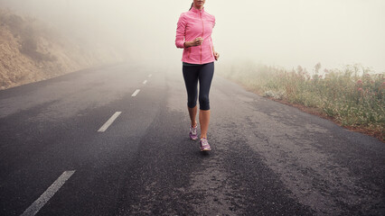 Canvas Print - Running, legs and woman on road outdoor in forest, park or woods for exercise in winter. Morning, fog and person with fitness training and healthy workout on path in mountain countryside with nature