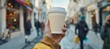 © Ilja - Male hand holding mockup paper coffee cup on blurred background with copy space for text