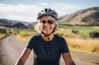 Portrait of happy senior woman wearing bicycle helmet and looking at camera in countryside