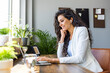© Dragana Gordic - Cheerful young businesswoman having a video call in a modern co-working space. Happy female entrepreneur communicating with her business associates while working remotely.