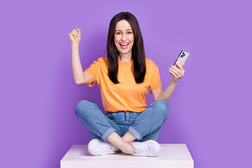 Sticker - Photo of successful mature business woman with smartphone sit podium and celebrating winning auction isolated on violet color background