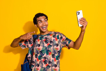 Wall Mural - Photo of student guy in stylish t shirt point finger into cadre recording video using smartphone isolated on yellow color background