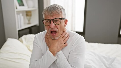 Wall Mural - Pain-stricken middle age, grey-haired man writhing in agony, suffocating from a painful strangle in his pyjama, an alarming health problem surfaces in the gloom of his bedroom.