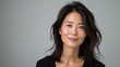 © Synthetica - Beautiful confident Asian woman of middle age posing for portrait. Pretty mature adult lady model from Asia looking at camera smiling on background advertising products and services. Close up face .