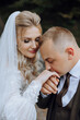 © Vasil - The groom kisses the bride's hand. Wedding photo of a couple in love. A young and handsome man kissing his wife's hand with a gold ring, proposing.