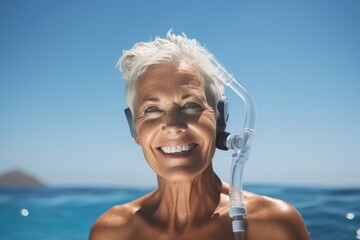 Wall Mural - Smiling senior woman with snorkel mask on blue sea background