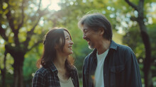 50代の日本人夫婦が新緑のきれいな公園を散歩している仲睦まじい様子