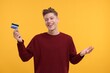 © New Africa - Happy man with credit card on yellow background