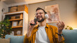 © Miljan Živković - One man adult hold smartphone mobile phone at home happy smile sing