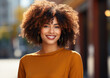 © Olga - The girl with dark curly hair stands on the street and smiles, generative AI