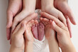 © Vad-Len - The palms of the father, the mother are holding the foot of the newborn baby in a white blanket. Feet of the newborn on the palms of the parents. Studio macro photo of a child's toes, heels and feet.