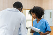 © Jack Tamrong - Black doctor man talking with black curly hair nurse at hospital registration counter