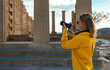 © M-Production - A woman tourist with a camera in the Acropolis on an excursion.