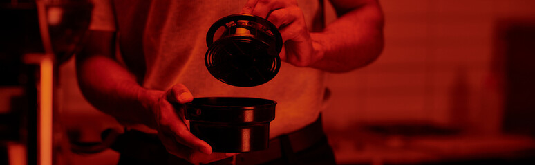 cropped banner of photographer holding film canister and developing photos in red darkroom