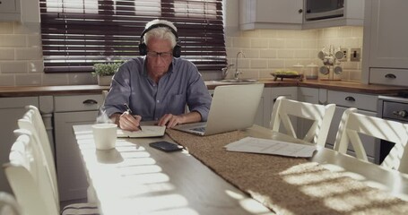 Poster - Home headphones, notebook and old man writing business information, schedule or summary of online report in kitchen. Laptop, journal and senior person doing research, remote work and listen to music