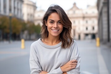 Wall Mural - Portrait of a beautiful young woman smiling with arms crossed in the street
