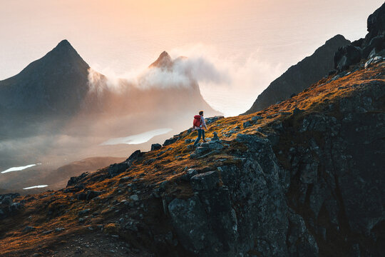 man climbing mountains traveling in norway tourist solo hiking in lofoten islands outdoor traveler w