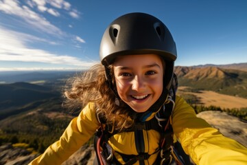 Wall Mural - Portrait of a smiling girl in helmet on the top of the mountain