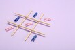 Tic tac toe game made with clothespins on lilac background