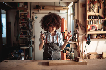 Wall Mural - Woman listening to music in a woodworking workshop