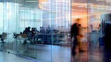 Fototapeta Uliczki - Blurred office with people working behind glass wall