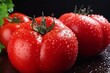 Three red tomatoes with water drops on a black background
