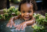 Fototapeta  - Cute joyful African baby bathes in a basin of water, looks at the camera