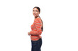 young slender adult woman with a ponytail dressed in an orange striped jacket and jeans is flirting on a white background