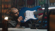 © Framestock - Male carpenter detailed inspects the guitar and strings. Craftsman makes musical instrument from wood in modern workshop. Another artisan works in the background. Handcraft and small business concept.