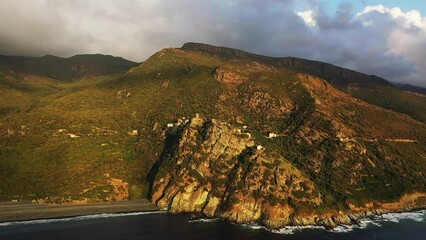 Wall Mural - The panoramic view of the village of Nonza in the middle of the mountains and by the beach, in Europe, in France, in Corsica, towards Bastia, by the Mediterranean Sea, in summer, on a cloudy day.