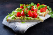 Traditionelles Toast Dreieck Sandwich mit Tomaten, Avocado Aufstrich und Kräuter serviert als Nahaufnahme auf einem grauen Design Tablett 