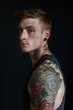 © ChemaVelasco - portrait of Caucasian boy with tattoos and black t-shirt on black background