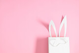 Fototapeta Tulipany - Easter party concept. Flat lay, top view of funny bunny ears on isolated pastel pink background. Easter decorations.
