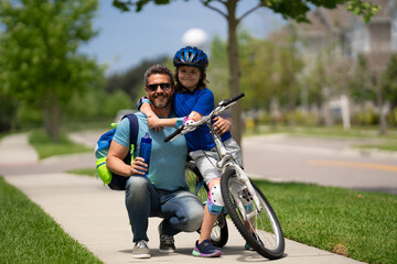 Wall Mural - Fathers day. Father teaching son ride a bicycle. Happy loving family. Father and son hugging. Father playing with son outdoor. Father support child. Fathers love. Sporty kids.