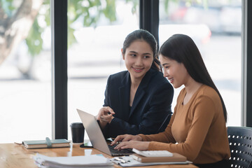 Wall Mural - Motivated young female office workers discussing business plan, using laptop in the office room.