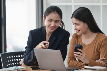 Wall Mural - Motivated young female office workers discussing business plan, using laptop in the office room.