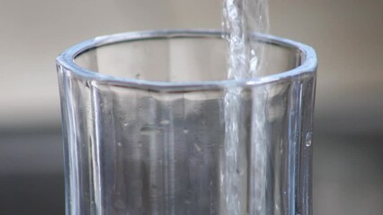 Filling up glass cup with sparkling clear water until it overflows