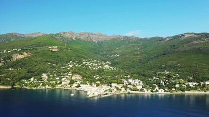 Wall Mural - The panoramic view of the city of Erbalunga in the middle of the arid and green mountains, in Europe, in France, in Corsica, towards Bastia, by the Mediterranean Sea, in summer, on a sunny day.