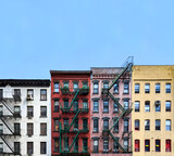 Fototapeta Miasta - Windows on colorful brick apartment buildings with empty blue sky background in Manhattan, New York City