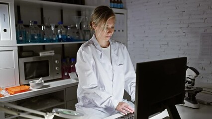 Poster - A focused woman scientist in a lab coat works on a computer in a modern laboratory setting