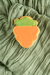 Sticker - Happy Easter, carrot shaped and decorated shortbread cookie on a pastel green gauze fabric background
